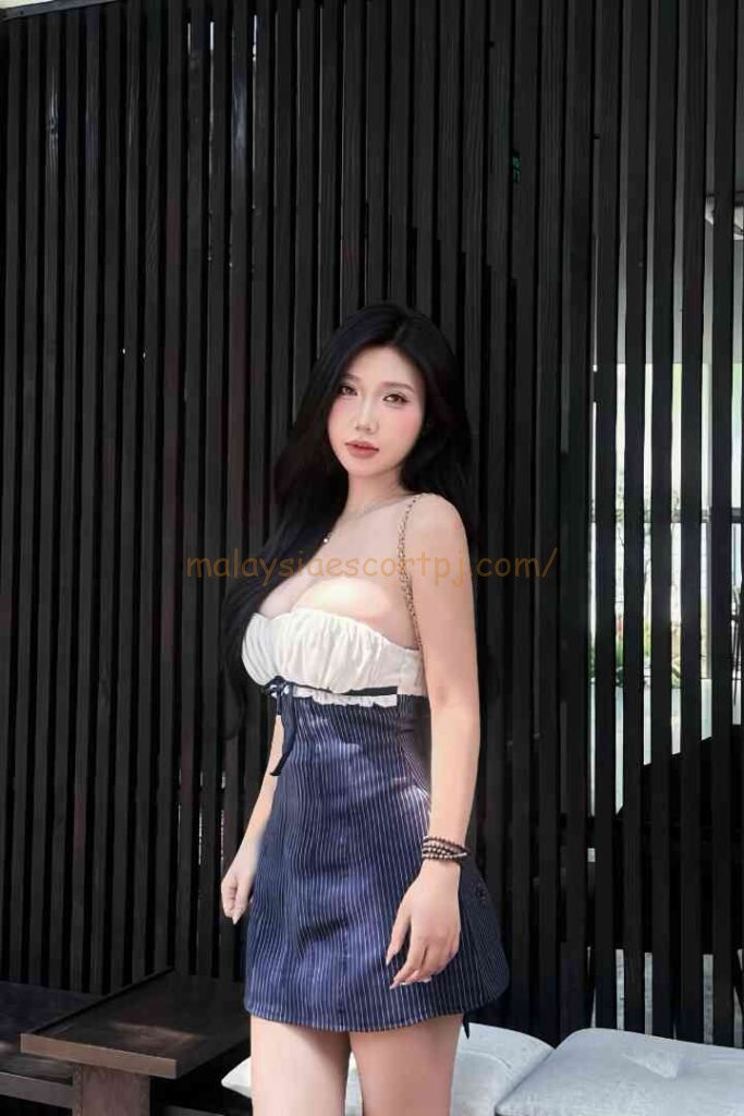 Yumi, a Vietnamese escort, poses in a striped dress.